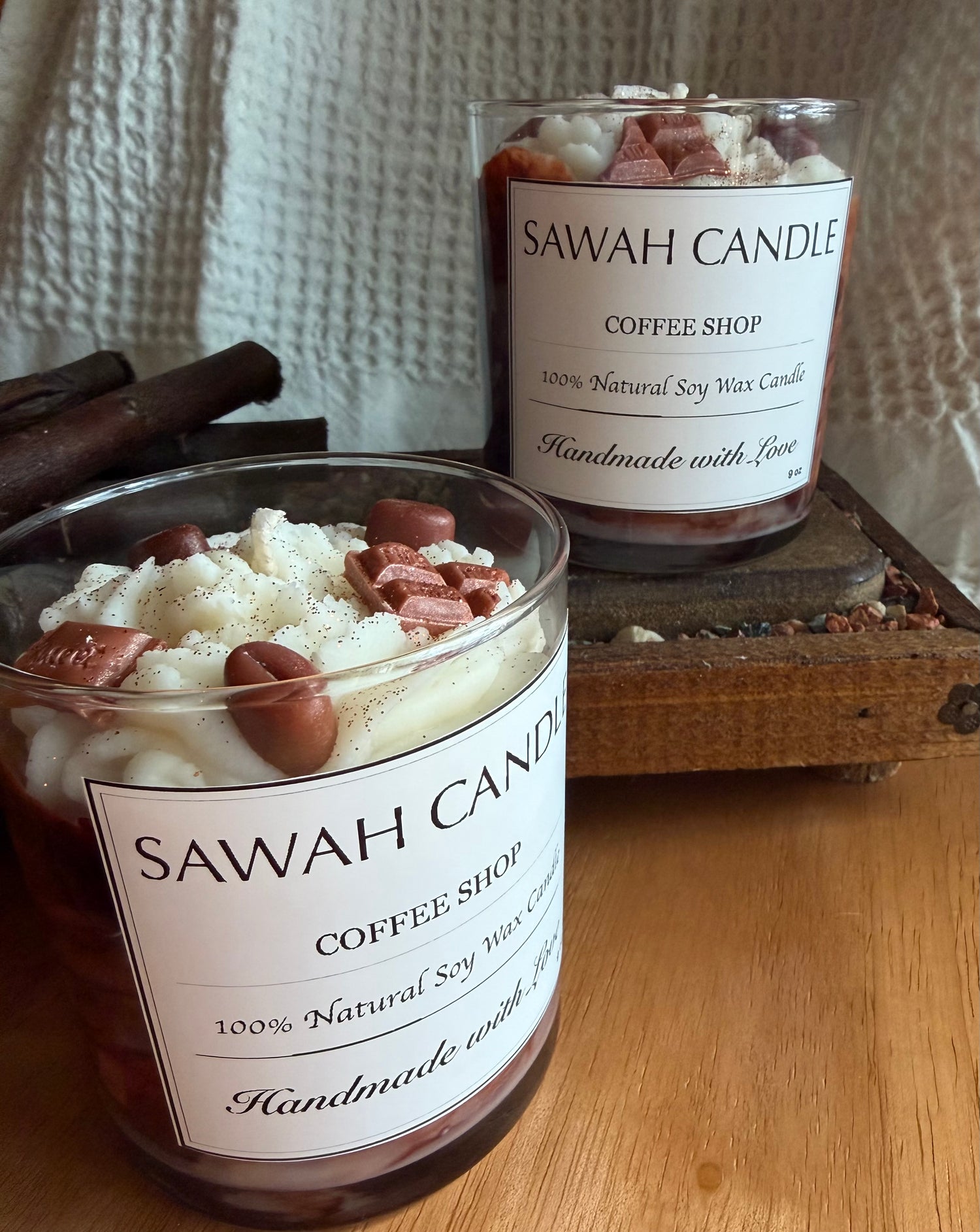Two SAWAH CANDLE Coffee Shop candles on a wooden surface with a textured white background.